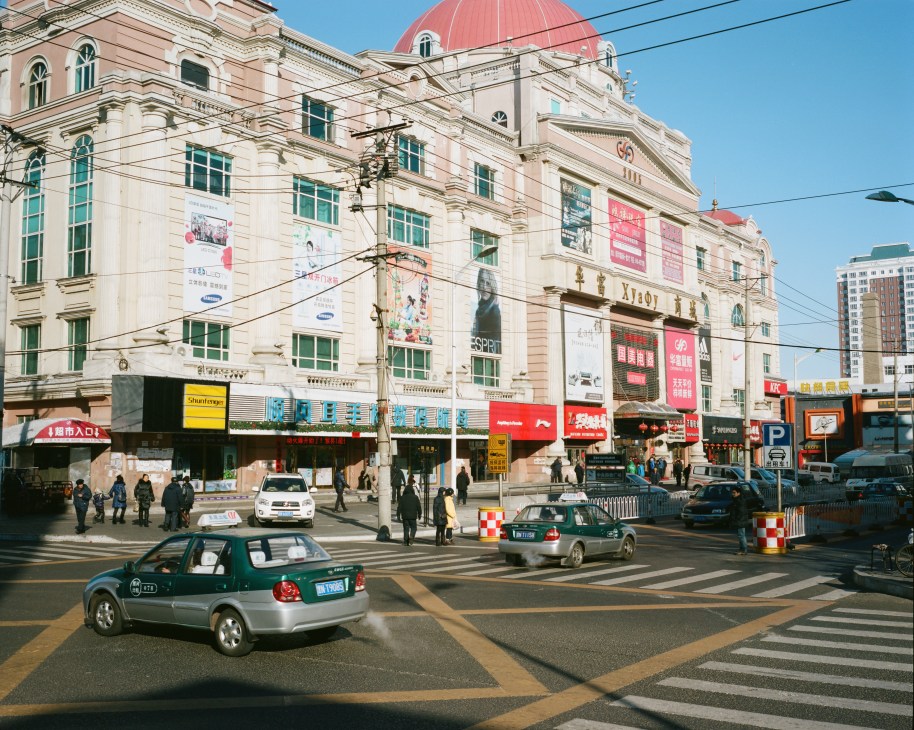 A multi-story neoclassical department store with a red dome in Heihe, China, with colorful advertising banners and commercial signage on its facade.