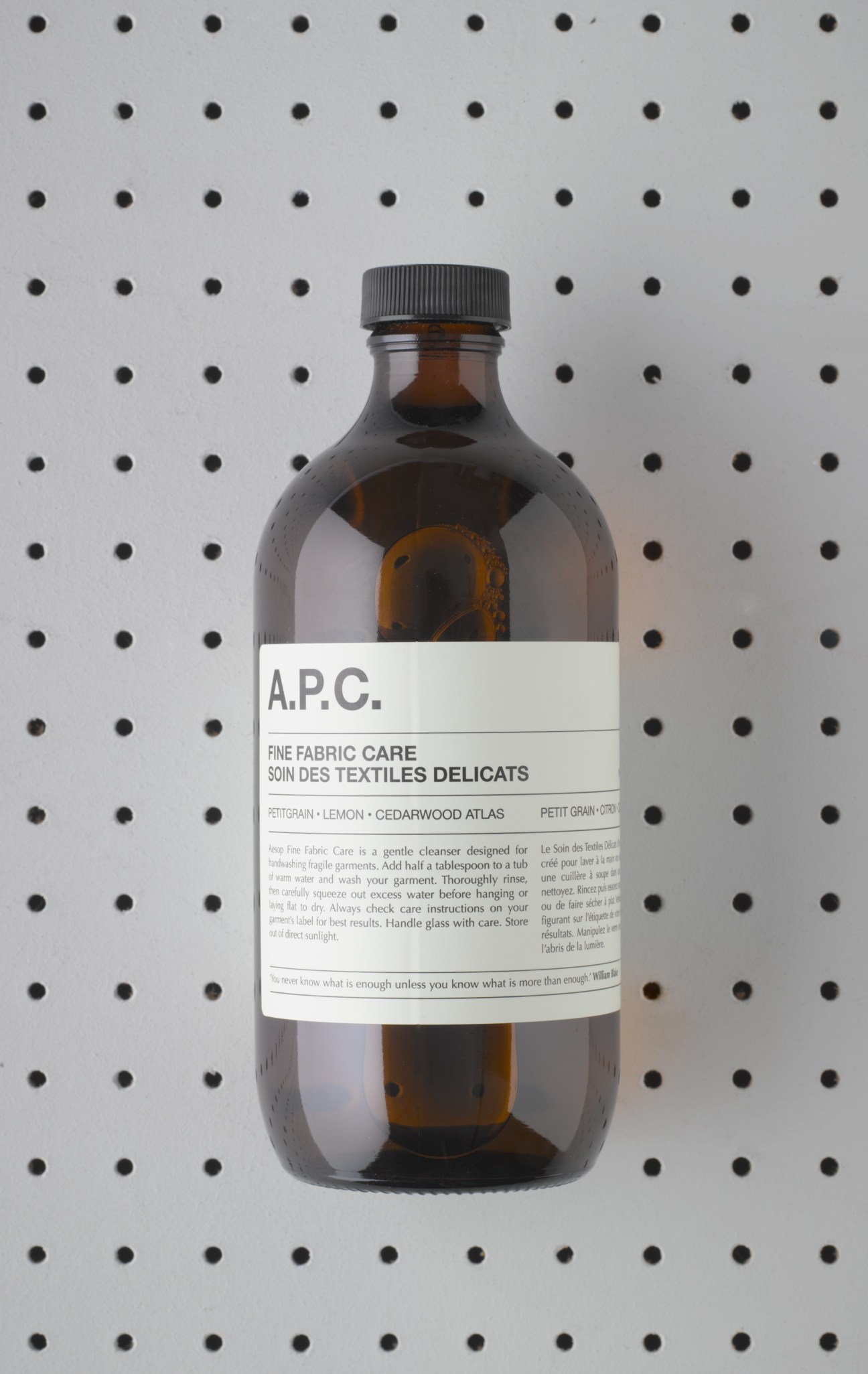 A.P.C. Fine Fabric Care cleanser bottle with pettigrain, lemon and cedarwood, against a dotted background.