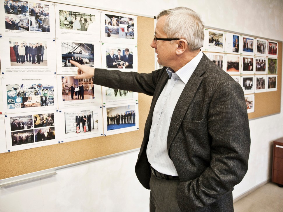 Marek Darecki, president of WSK PZL Rzeszów, pointing at historical photographs on a cork board display.