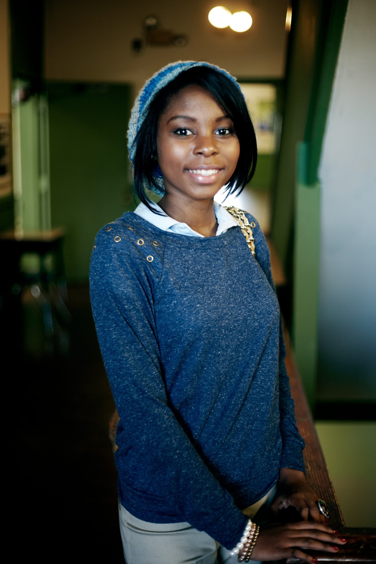 A young student smiles in a school hallway with green walls.