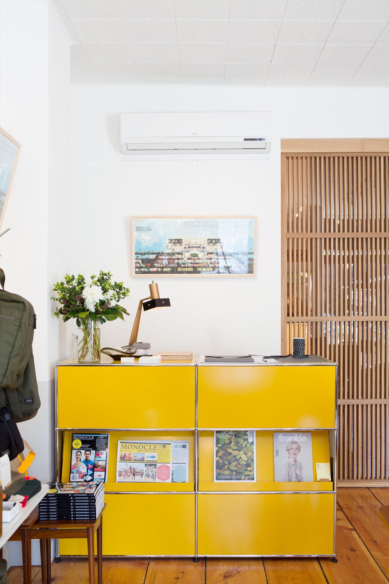 Staff member sits behind a bright yellow USM Haller modular furniture counter in The Monocle Shop Toronto location.