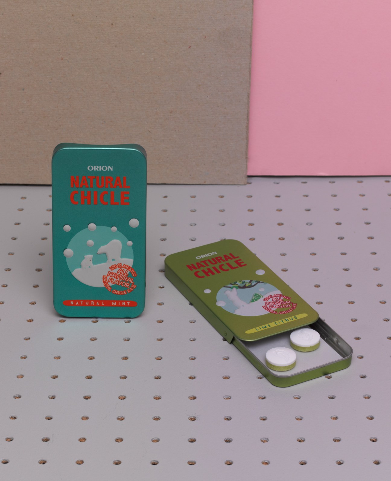 Orion Natural Chicle chewing gum packets in teal and olive green packaging displayed on a textured surface.