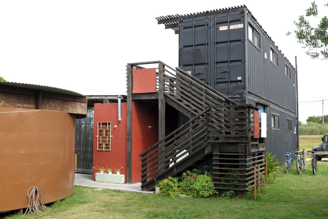 El Estrecho Paradiso hostel made from stacked black freight containers with red entrance building in La Pedrera, Uruguay.