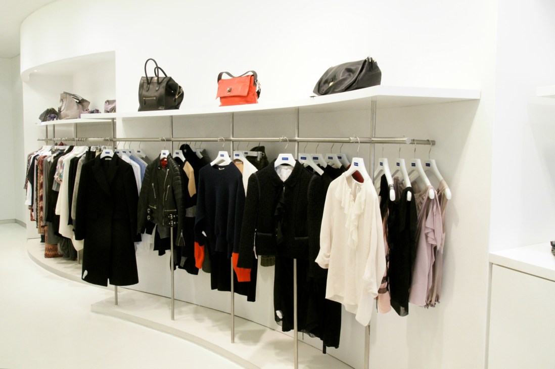 Interior of Feldenkirchen boutique displaying women's clothing on racks and handbags on shelves.
