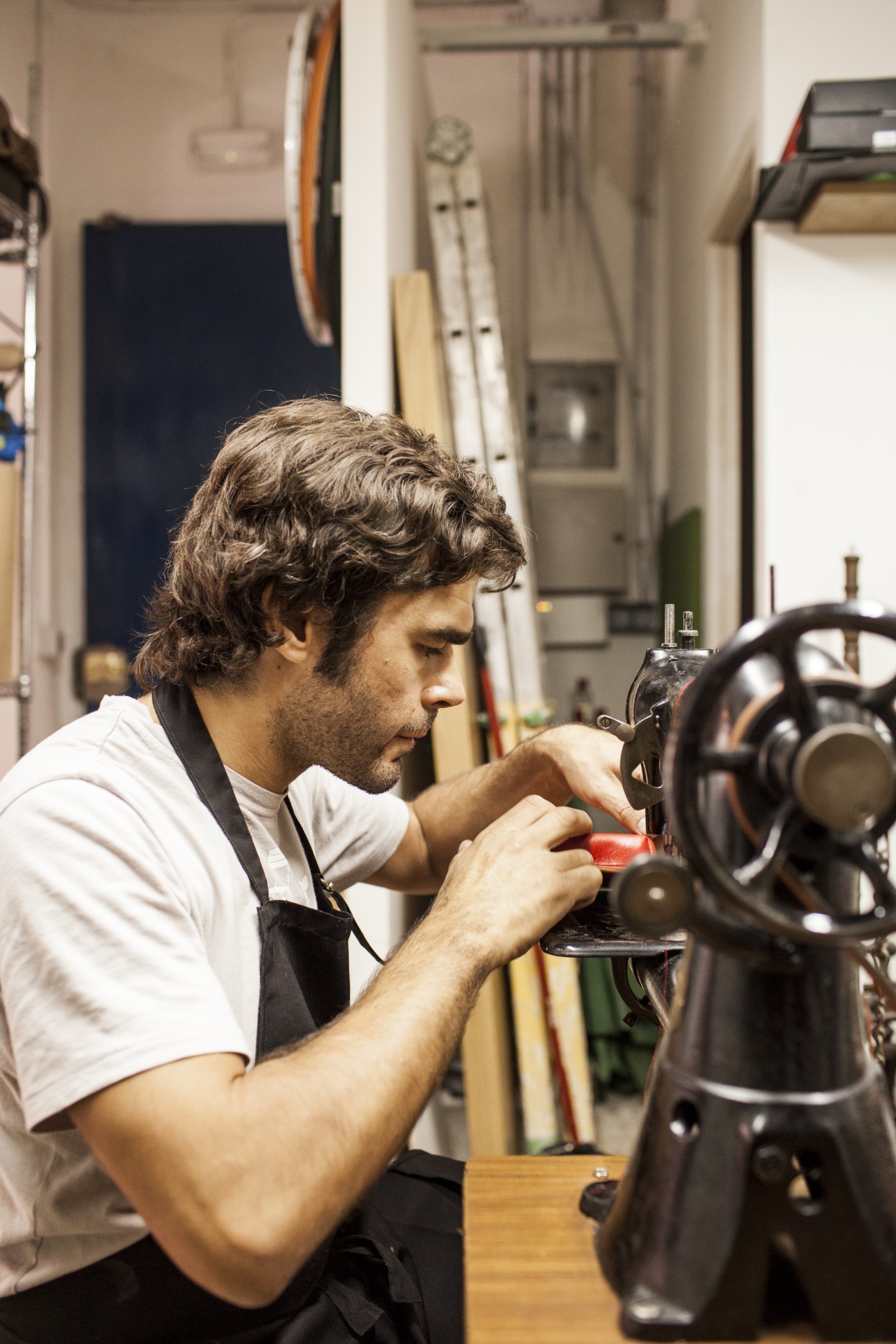 Pablo del Barrio working on a leather goods item at a sewing machine in his workshop.