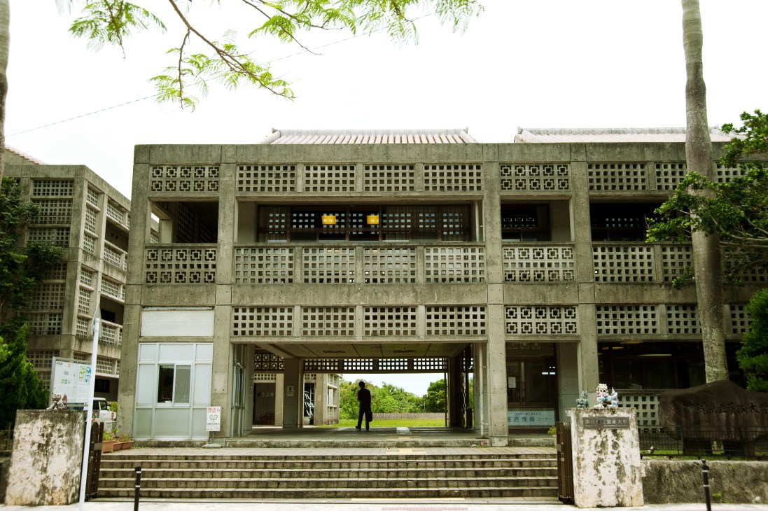 Concrete modernist building with geometric lattice screens and central open gallery at Okinawa Prefectural University of the Arts.