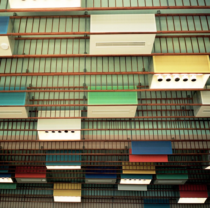 Ceiling detail showing multicoloured lightboxes with wooden rails and green panelling designed by Finn Juhl.