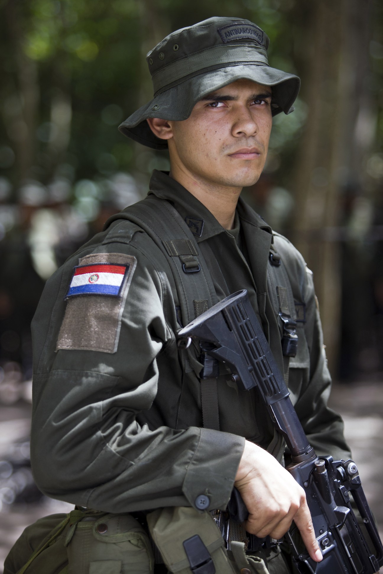 Paraguayan police student in tactical uniform with rifle and national flag patch.