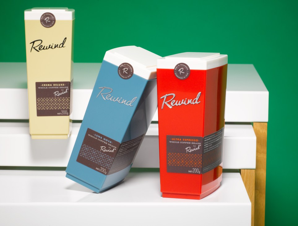 Three colorful Rewind coffee canisters in retro 1950s car-brand styling on a white display table.