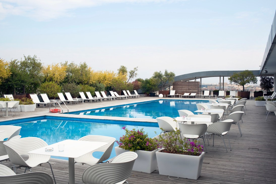 Radisson Blu es. Hotel rooftop pool with lounge chairs and city views of Rome.