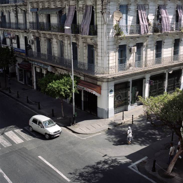 Colonial-era Parisian-style corner building in Algiers with shuttered windows and ornate ironwork balconies.