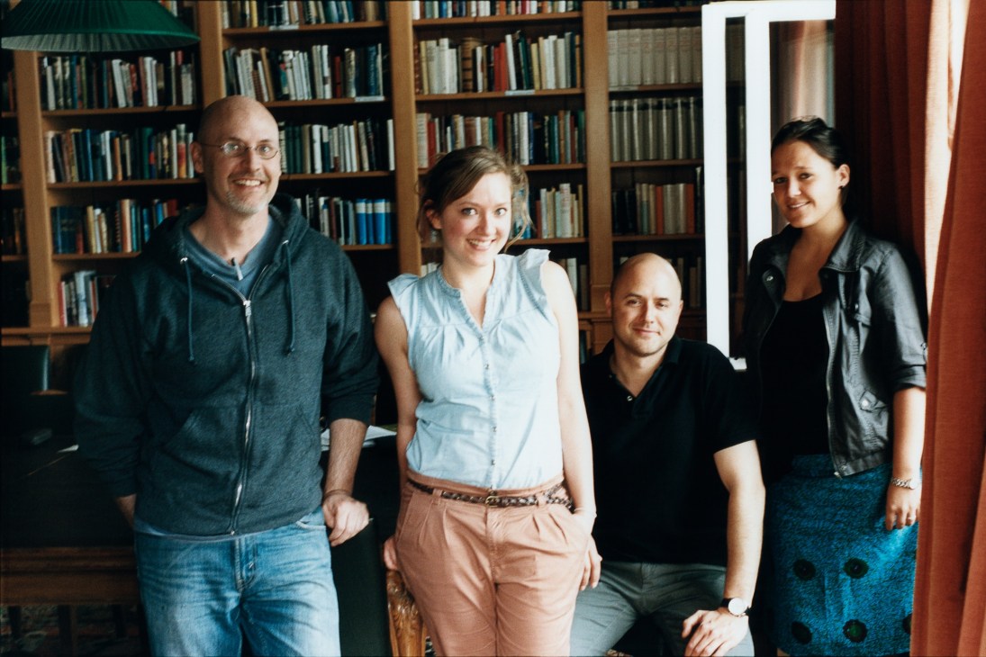 Five people smiling in front of bookshelves at the American Academy in Berlin.