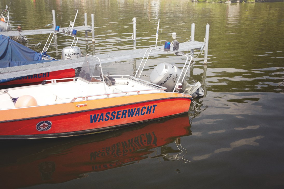 Red and white Wasserwacht rescue boat moored at a dock on Wannsee lake in Berlin.