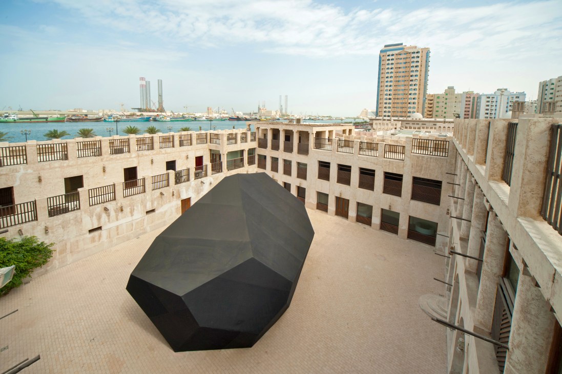 'Infinite Rock' by Thilo Frank, a large black geometric sculpture in a courtyard at Sharjah Biennial 11
