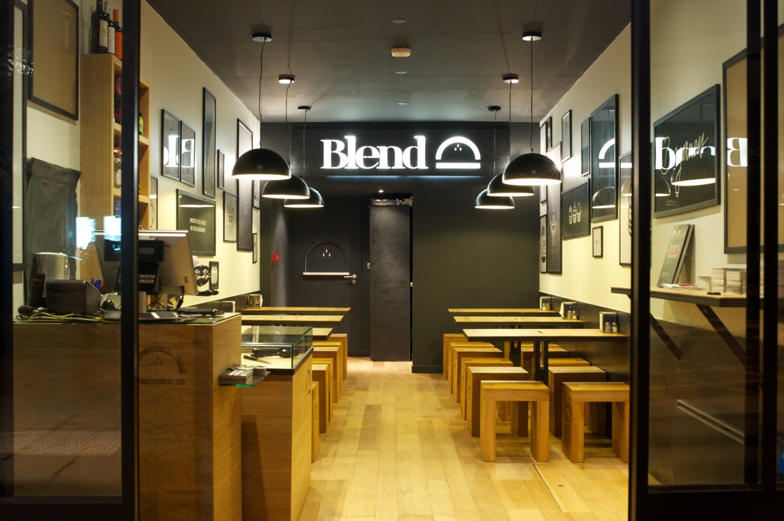 Interior of Blend burger restaurant in Paris with sleek black and wood design, pendant lighting, and counter seating.