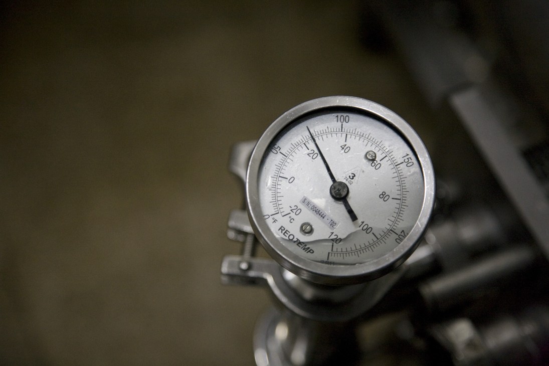 Close-up of an industrial pressure gauge with temperature markings used in beer brewing equipment.