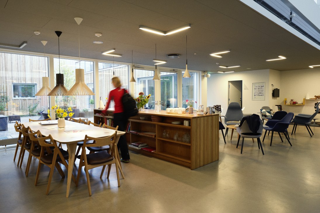 Bright café and reception area with wooden furniture, pendant lights, and views of an interior courtyard.