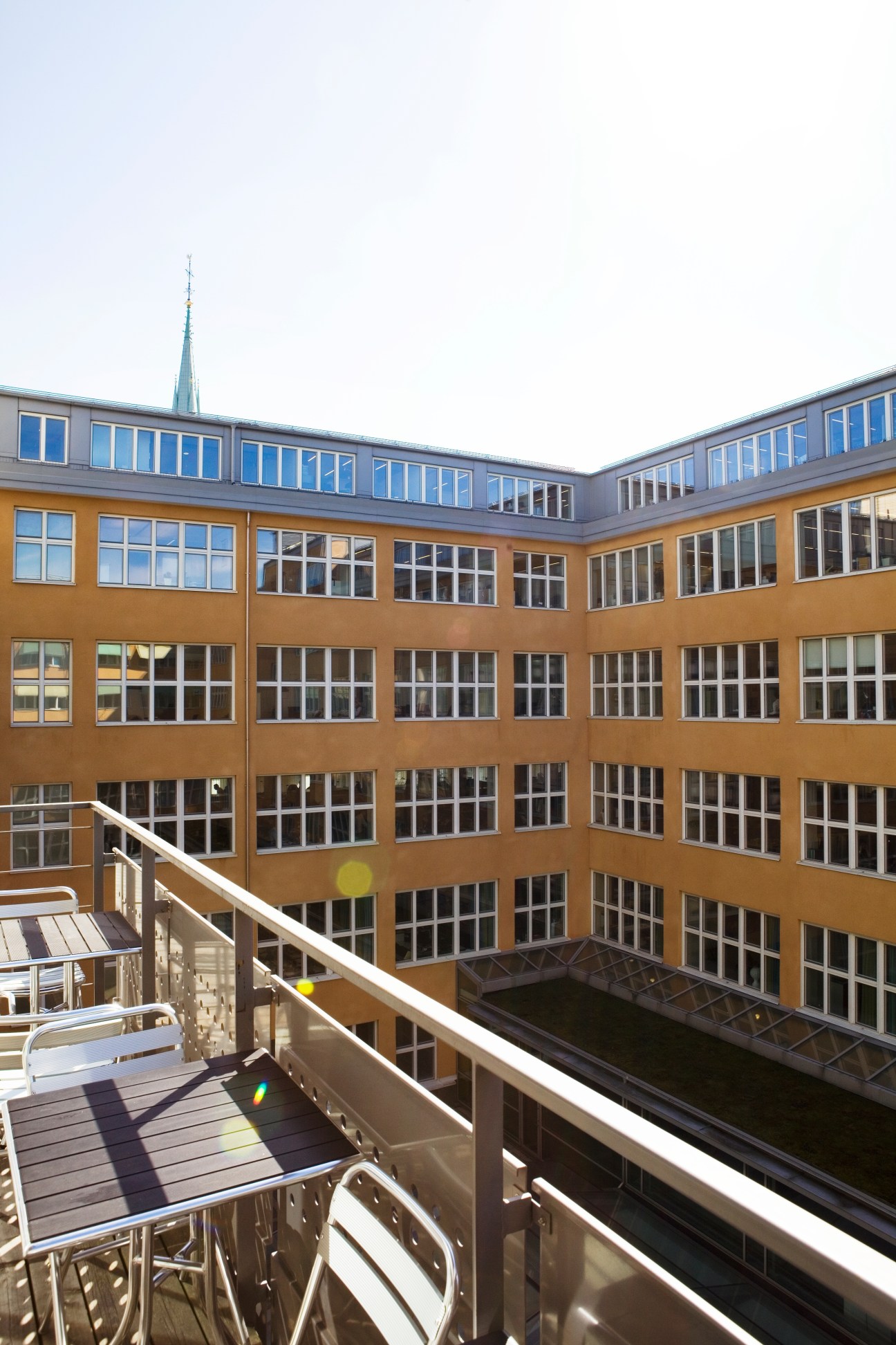 Balcony overlooking a modern courtyard with ochre-coloured building facade and multiple windows