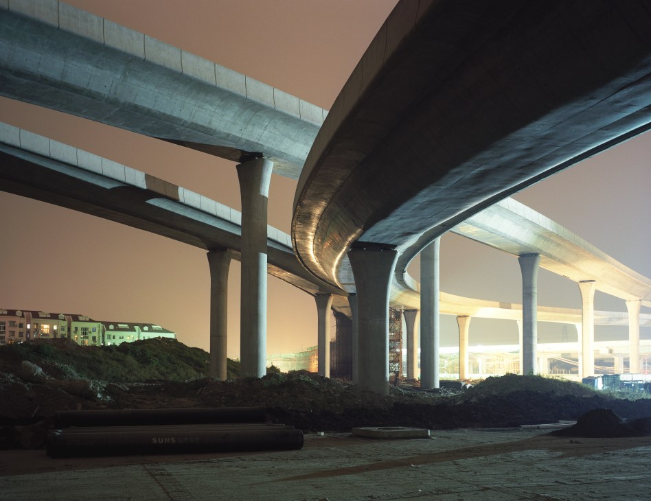 Illuminated highway overpass with multiple concrete support pillars at dusk near Shanghai.