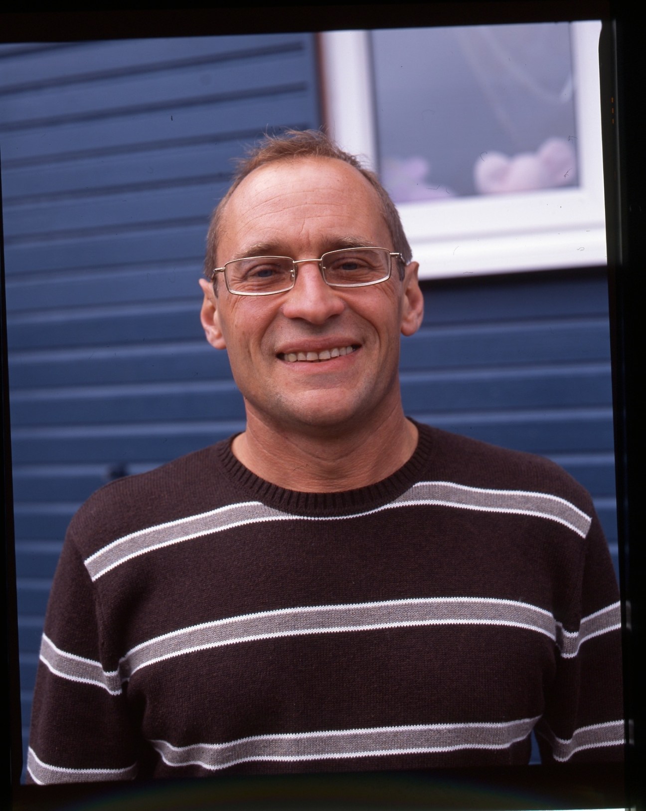 Portrait of Vladimir Laptikhovsky, a Russian-born Fisheries Department scientist, smiling at the camera wearing glasses and a brown striped sweater.