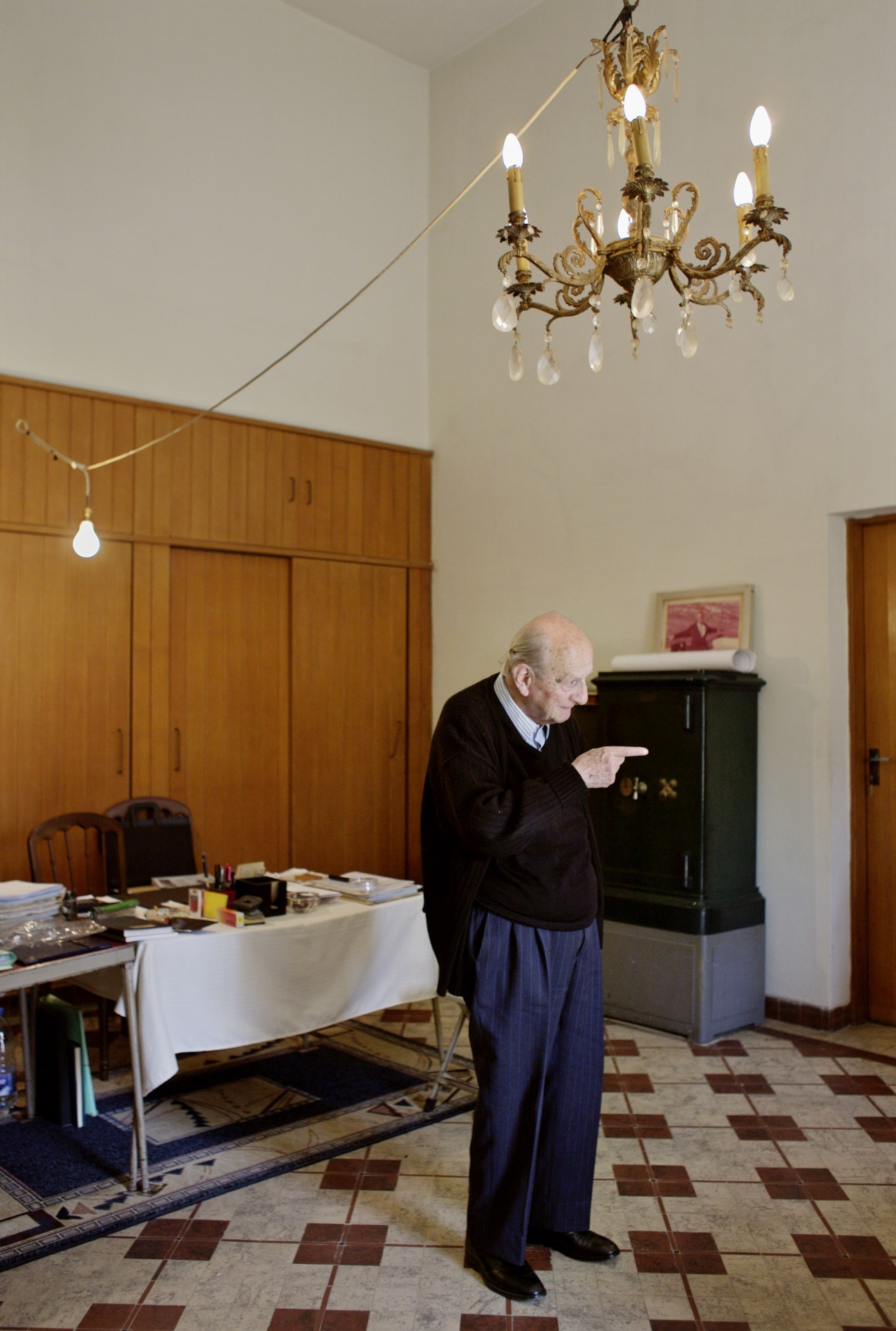 George Kassab, elderly man in dark suit, standing in ornate room with chandelier and wooden furnishings in Sursock villa.