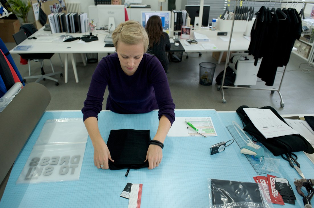 Designer Lisa Hjelm works at a table in Mover's open-plan headquarters, folding black fabric samples.
