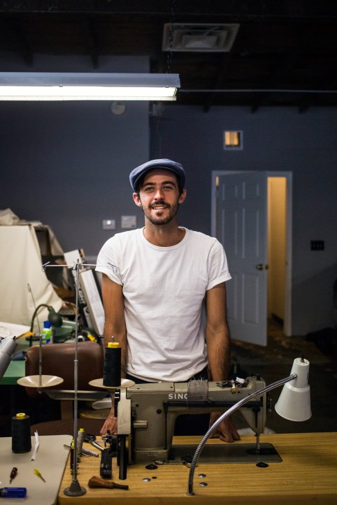 Menswear designer Otis James smiles at his workstation in his studio.