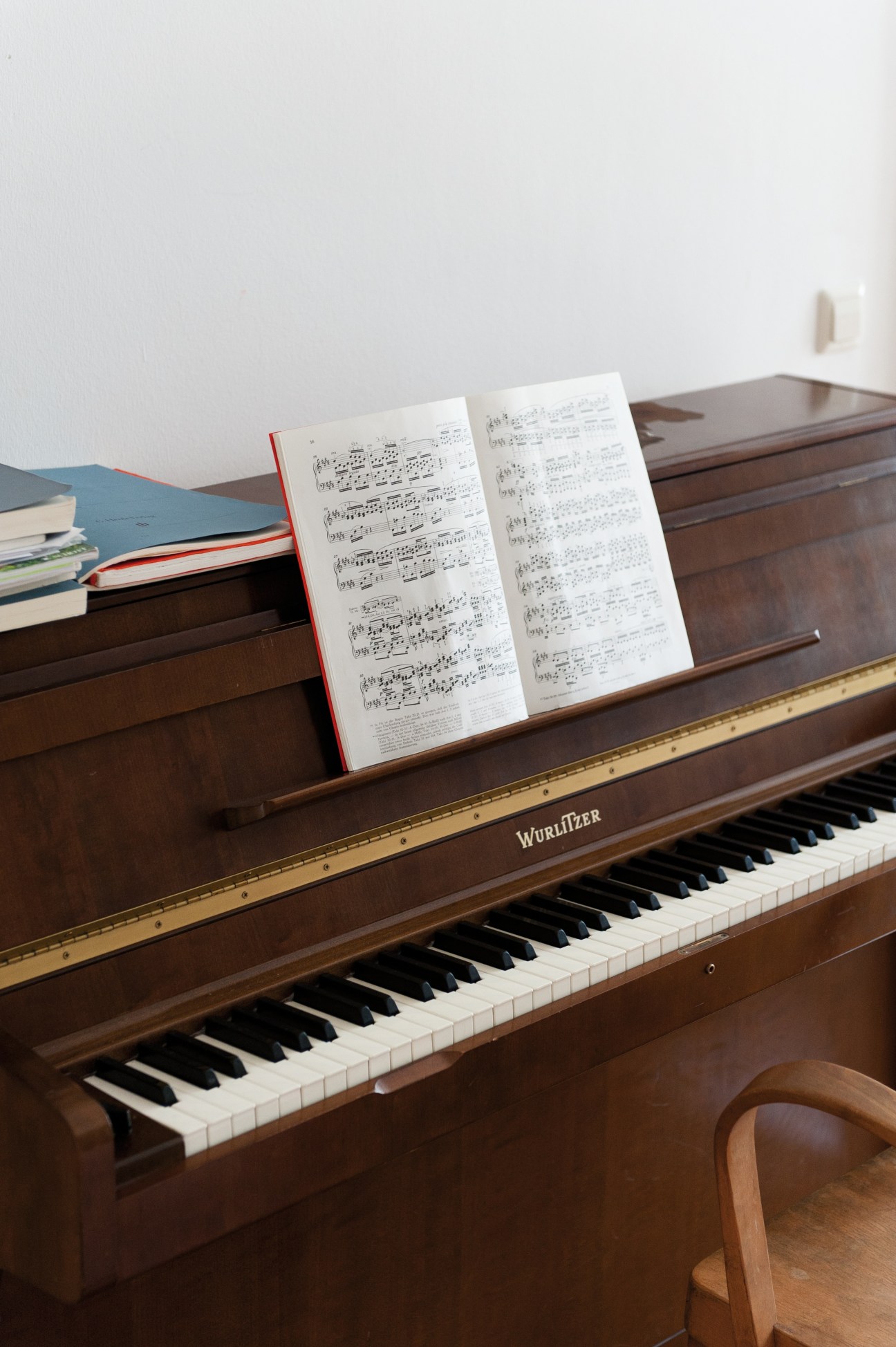 A Wurlitzer piano with sheet music and books displayed on top.