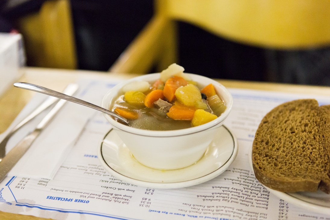 Bowl of lihamojakka Finnish meat stew with vegetables served at a restaurant table with dark rye bread.