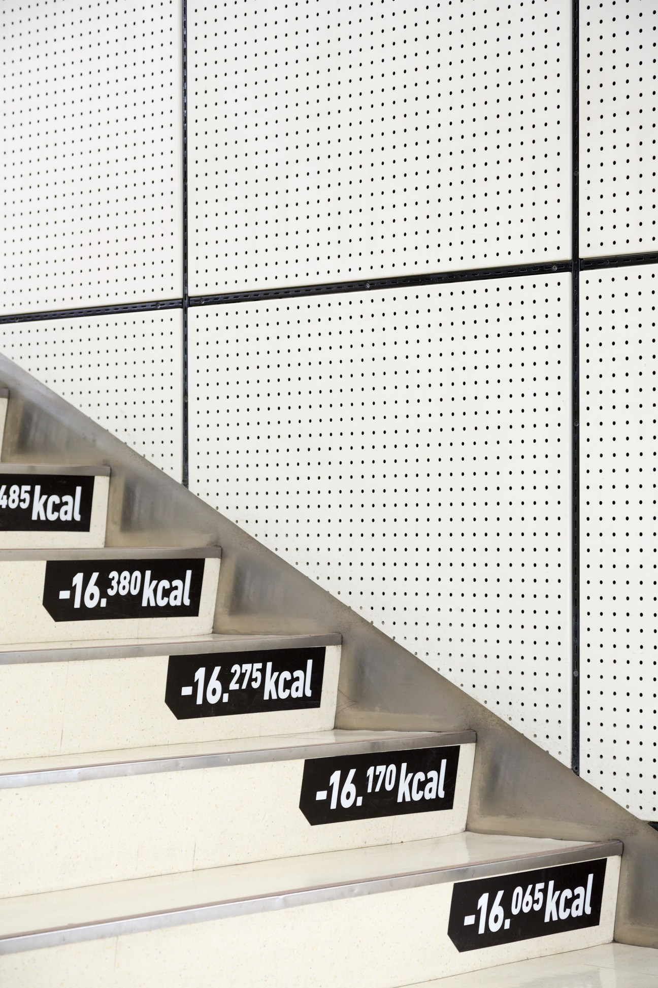 Staircase with calorie burn labels on each step against white pegboard wall.