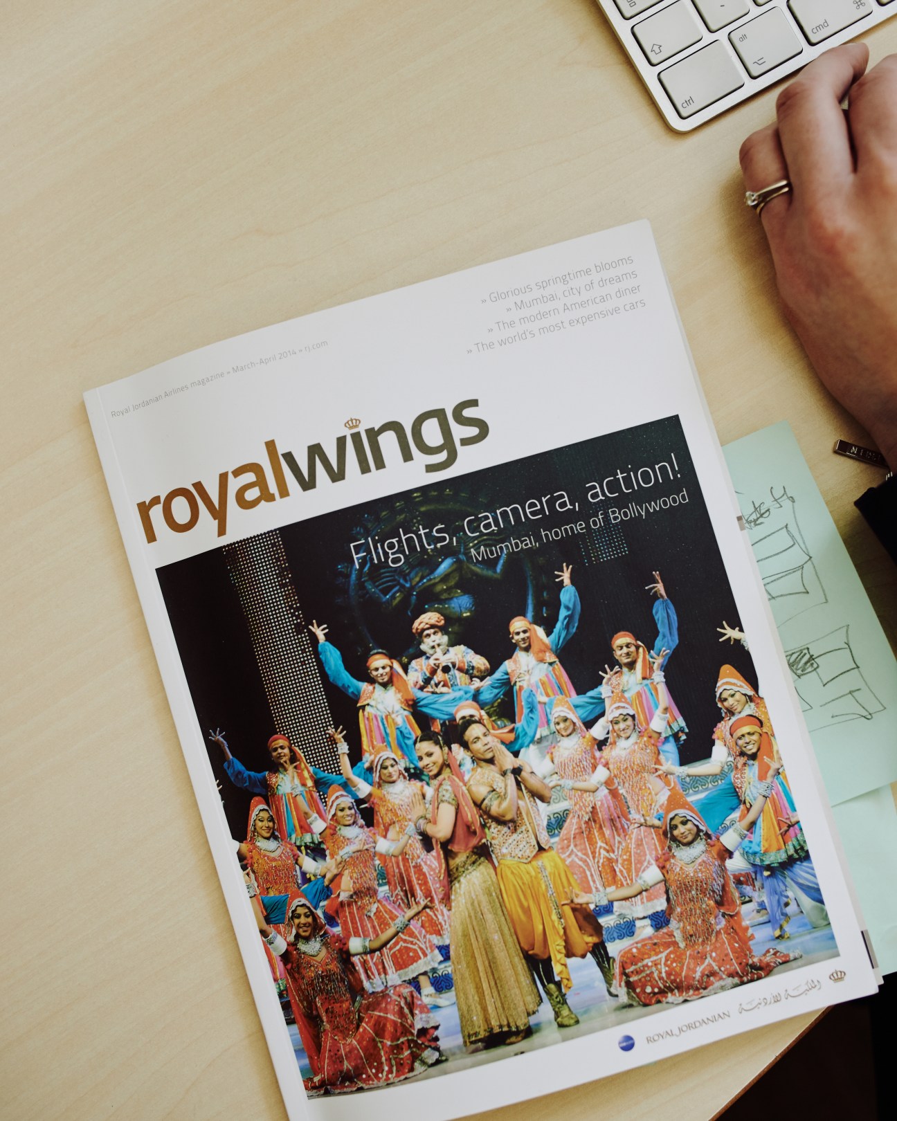 Royal Jordanian's Royal Wings in-flight magazine lying on a wooden desk next to a keyboard