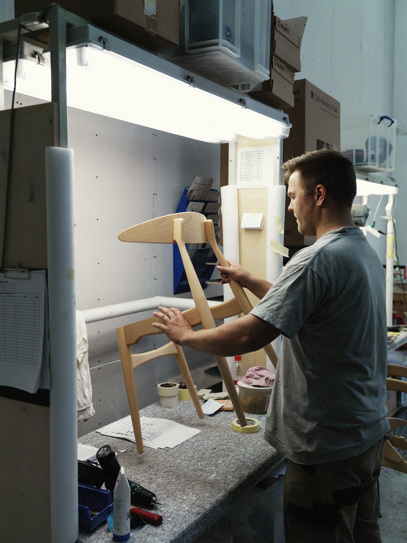 A craftsman works on assembling Hans J Wegner's CH33 wooden chair at Carl Hansen & Søn's factory.