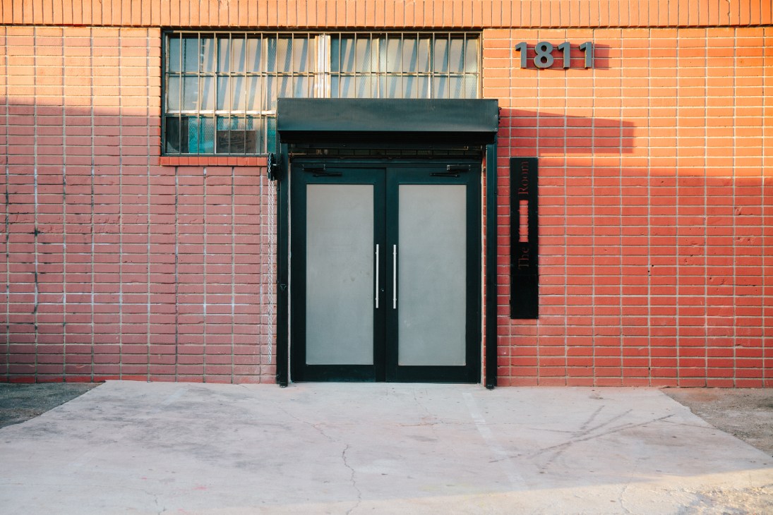 The Mistake Room's front entrance with black double doors on a red brick warehouse facade.