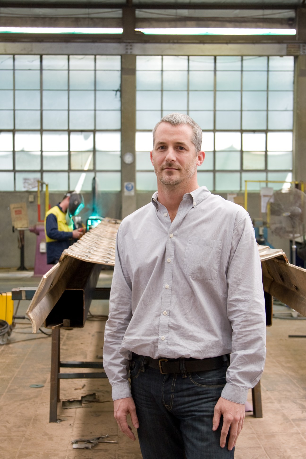 Daniel Tobin, co-founder of Urban Art Projects, stands in an industrial workshop setting.