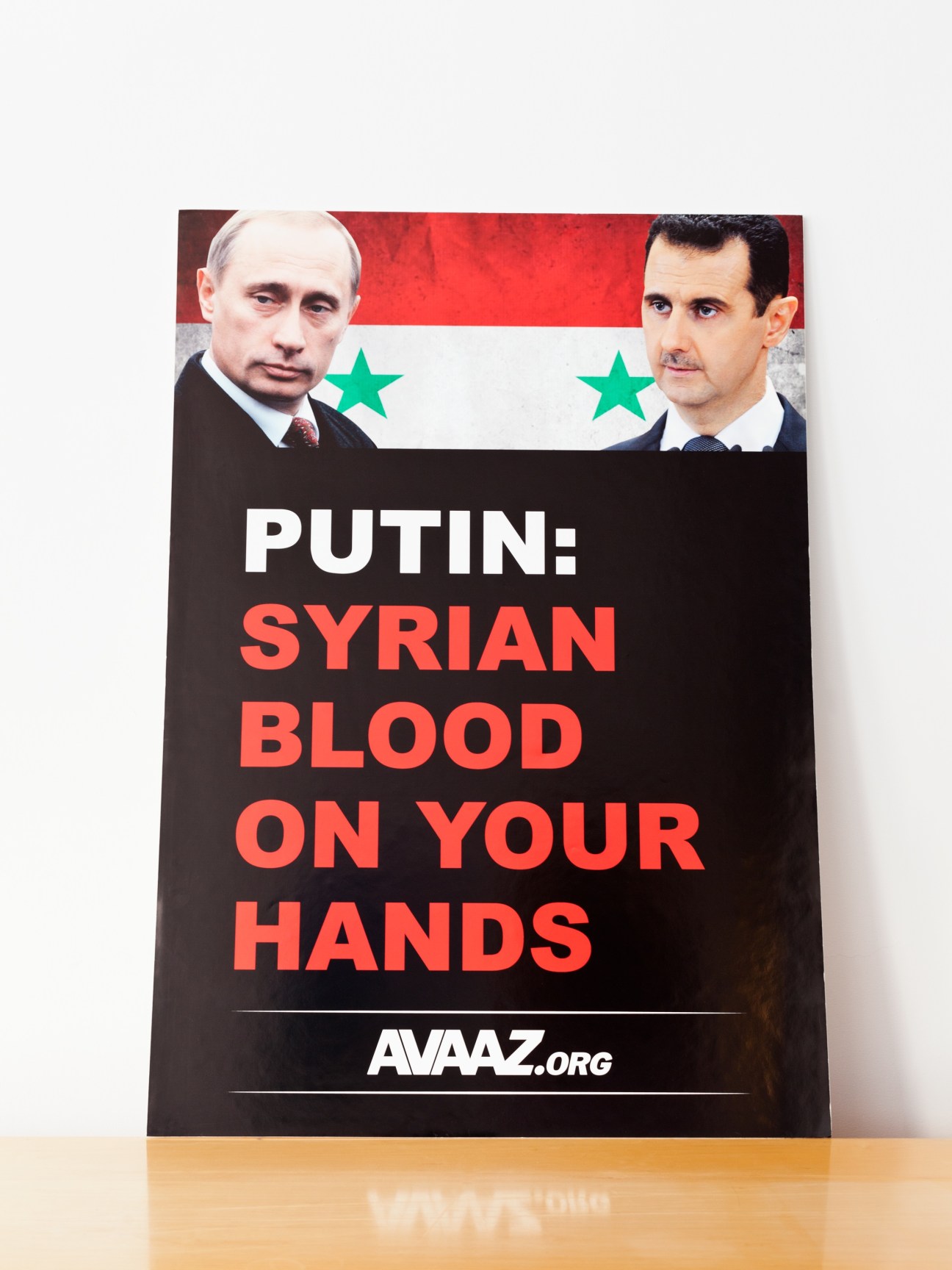 Avaaz campaign poster featuring Putin and Assad with Syrian flag and text accusing Putin of Syrian blood on hands.