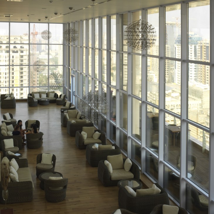 Modern high-rise bar with floor-to-ceiling windows overlooking Baku's cityscape and Caspian Sea.