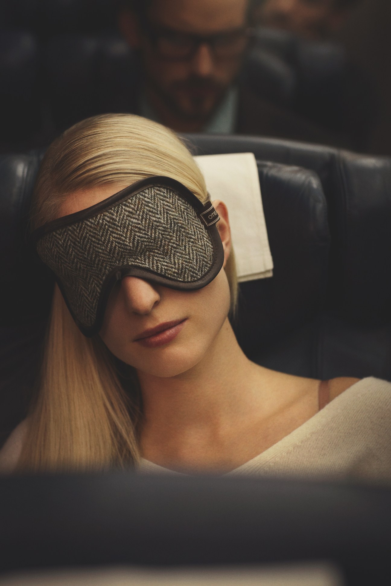 Woman wearing Otis Batterbee herringbone eye mask and Galerie Vie dress on an airplane.
