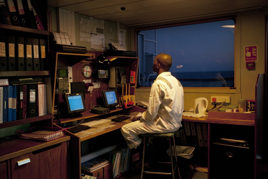Officer monitoring navigation equipment in the RMS St Helena's control room at dusk.