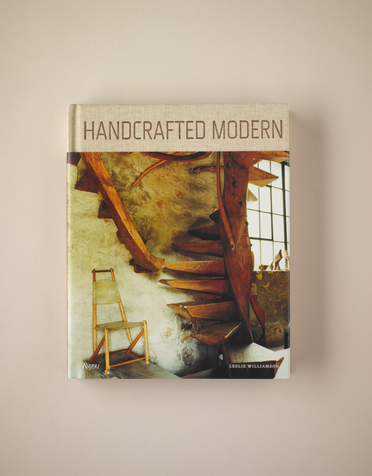 Book cover of 'Handcrafted Modern' by Leslie Williamson showing wooden furniture and staircase interior.