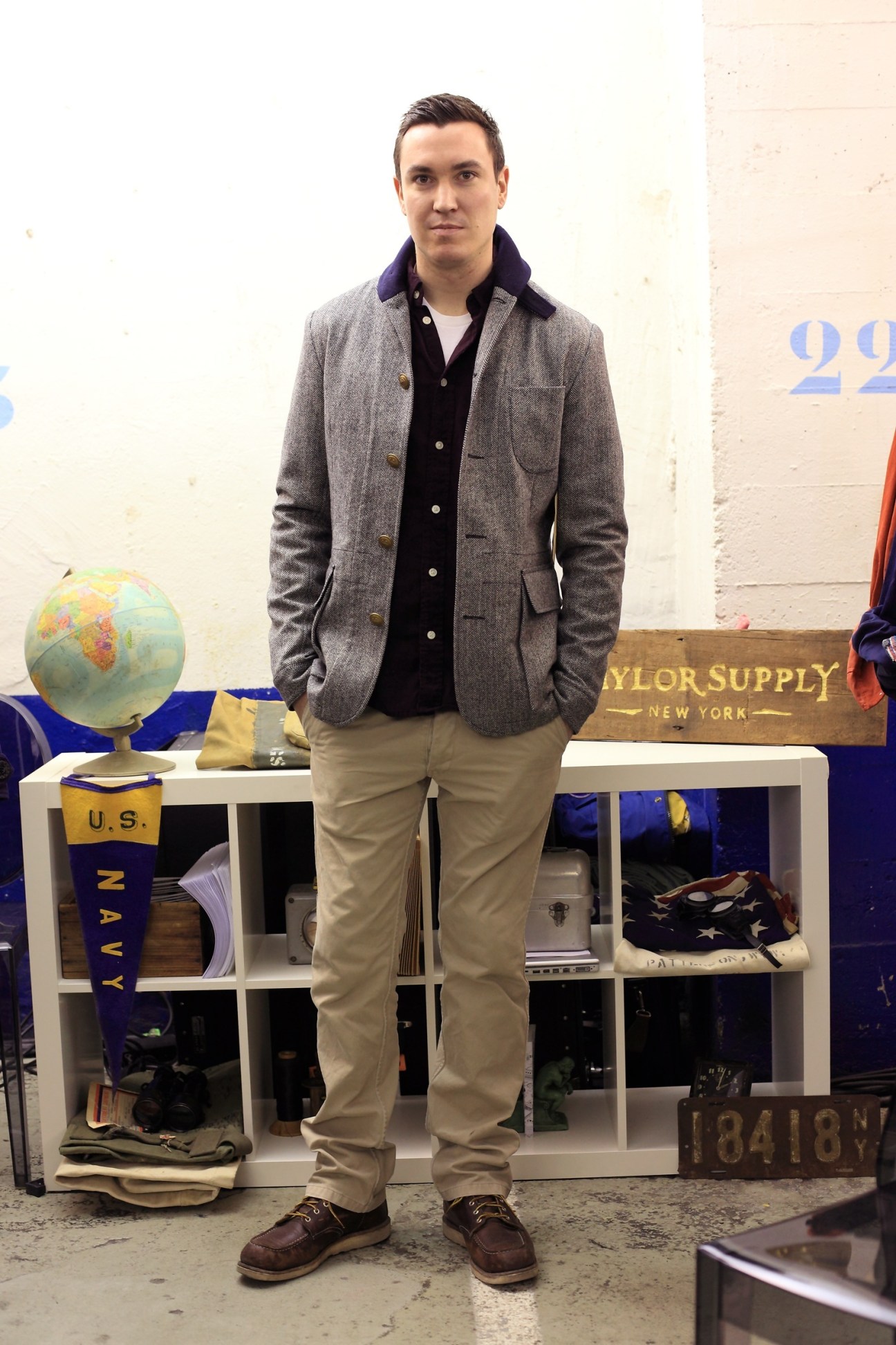 Man wearing grey blazer and beige trousers standing at Taylor Supply trade show stand.