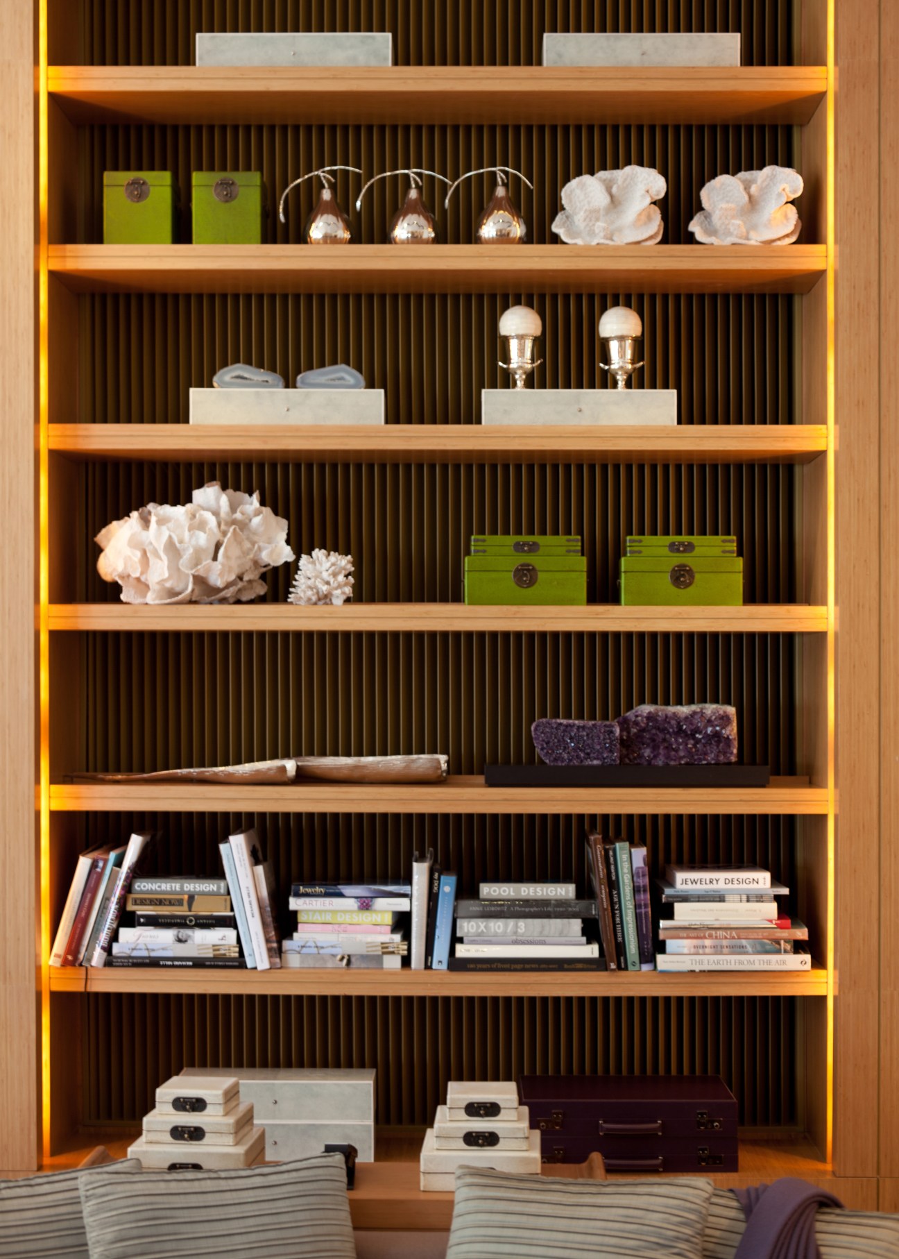Illuminated wooden shelving unit displaying decorative objects, books, and design accessories in The Upper House hotel room.
