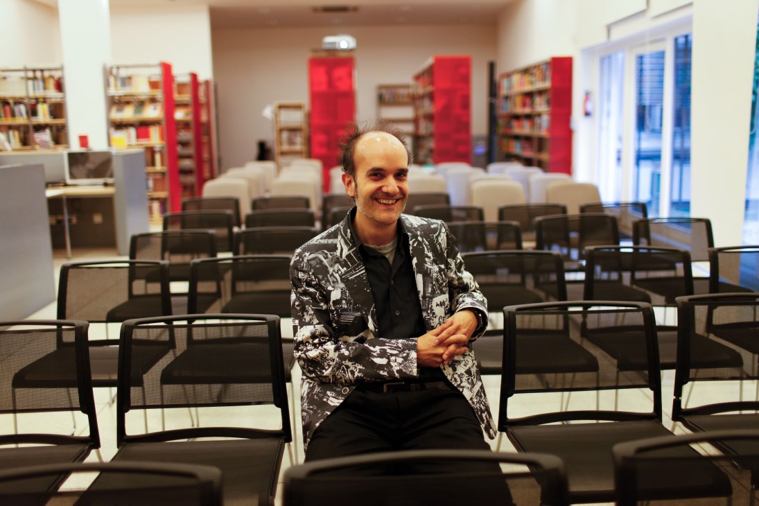 Robin Mallick, regional programme director South Asia, sitting in an auditorium with red bookshelves and black chairs at the Goethe-Institut New Delhi.