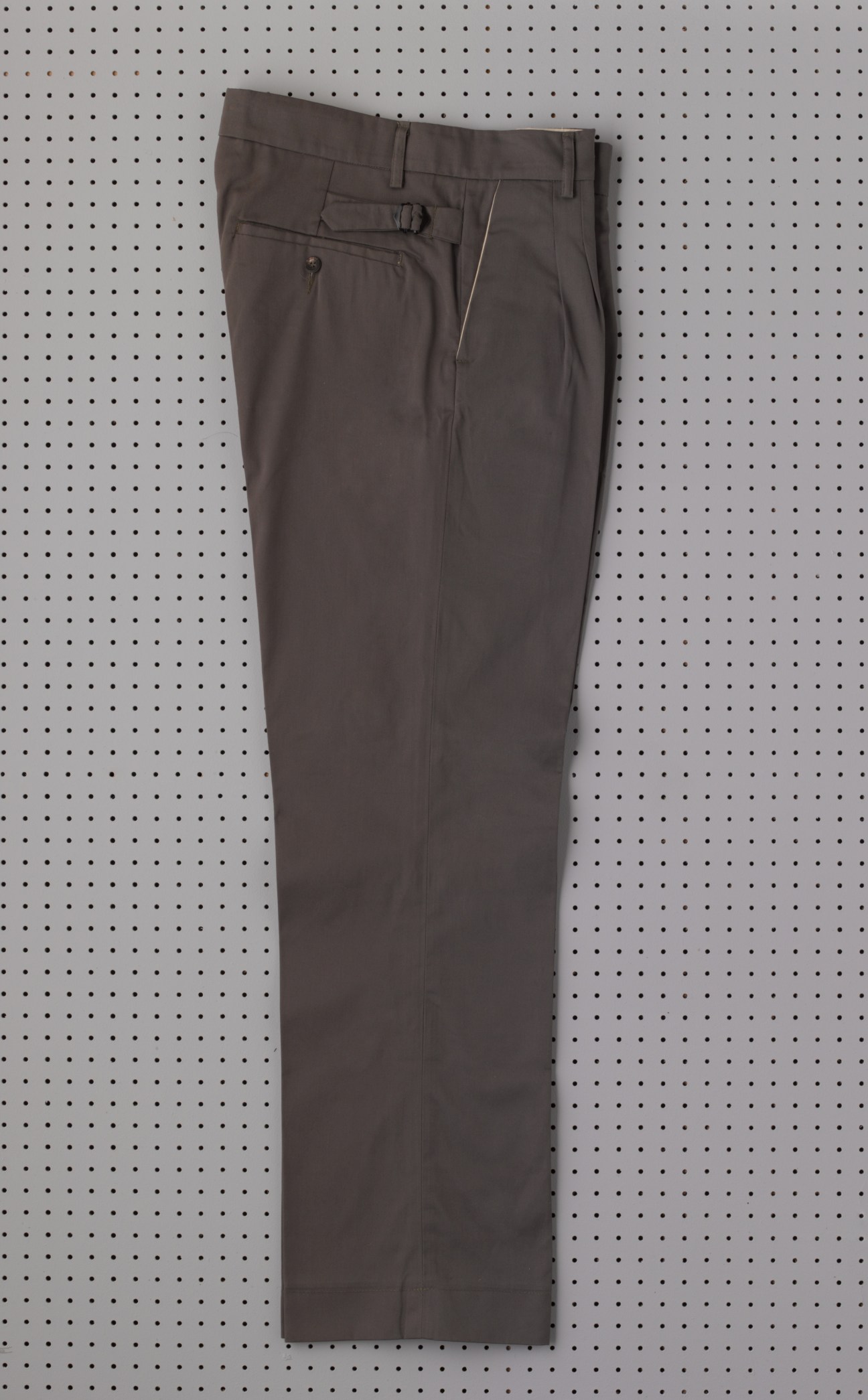 Charcoal grey trousers displayed flat against a white pegboard background.