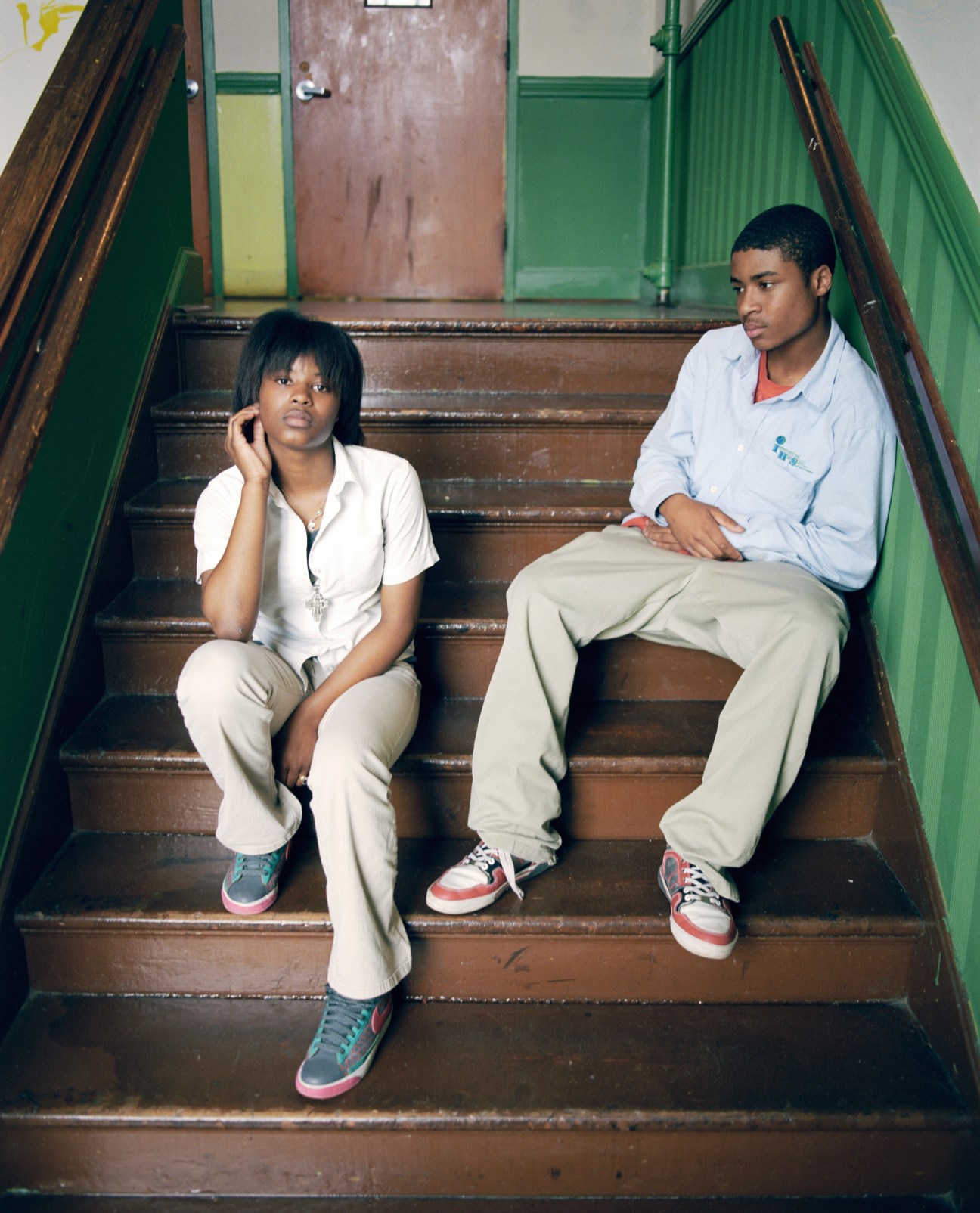 Two International High School students, Earlneshka Johnson and Terrence Thomas, sit together on a staircase with green walls.