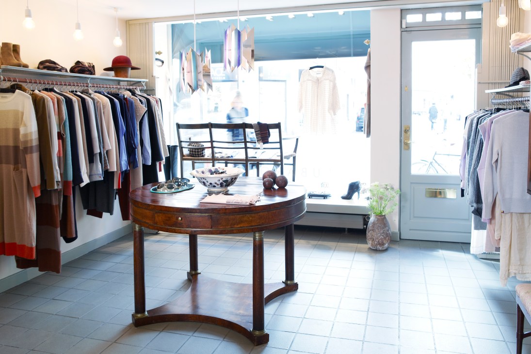 Interior of Lubarol boutique in Copenhagen showing clothing racks and a round wooden display table.