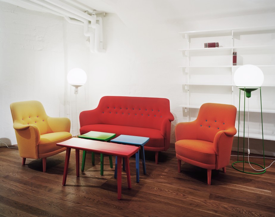 Colorful Samsas armchairs and sofa in red, orange and yellow upholstery arranged around a multicolored coffee table in a minimalist white interior.
