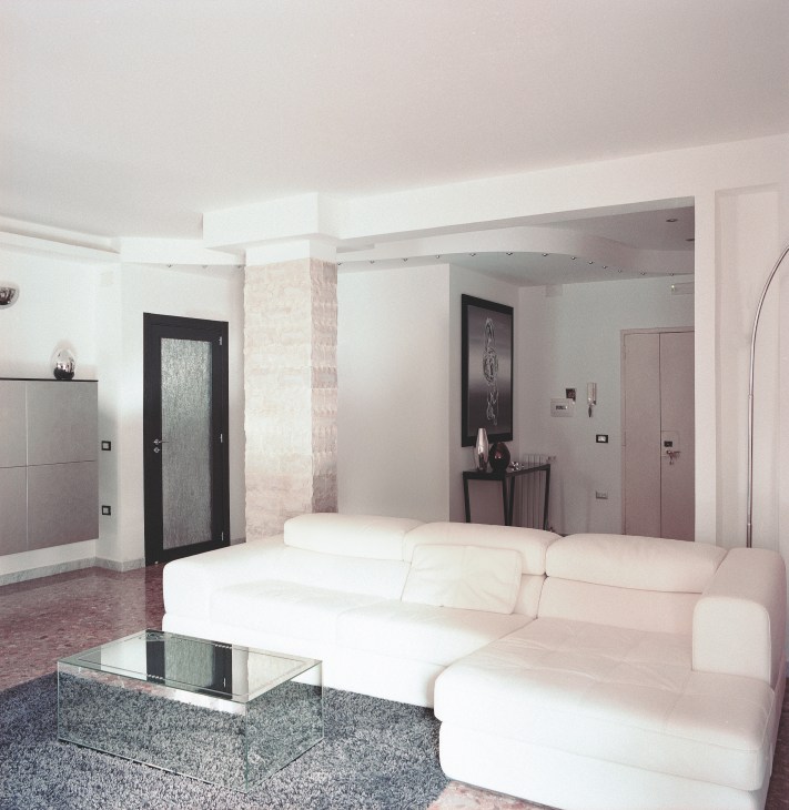 Contemporary interior living room with cream-colored sectional sofa, glass coffee table, and modern furnishings in neutral tones.