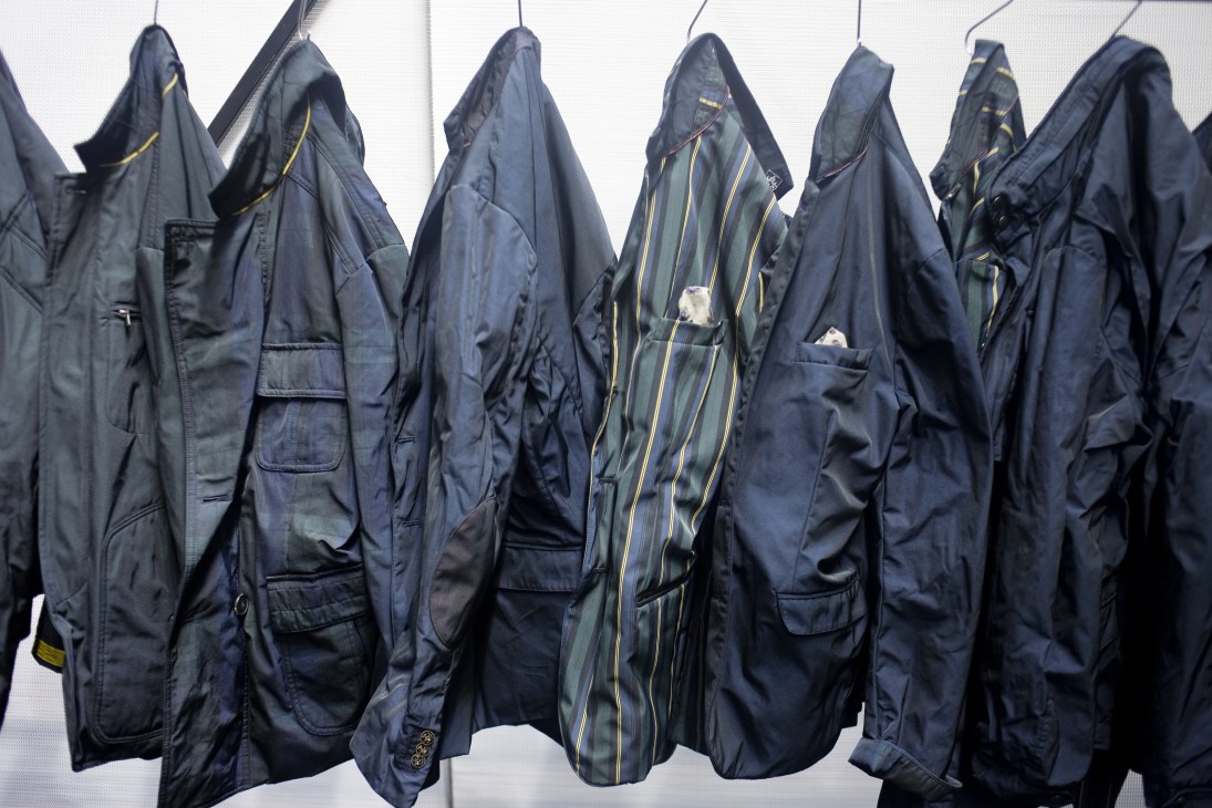 Navy nylon jackets with contrast checks and prints hanging on a rail at Pitti Uomo menswear show.