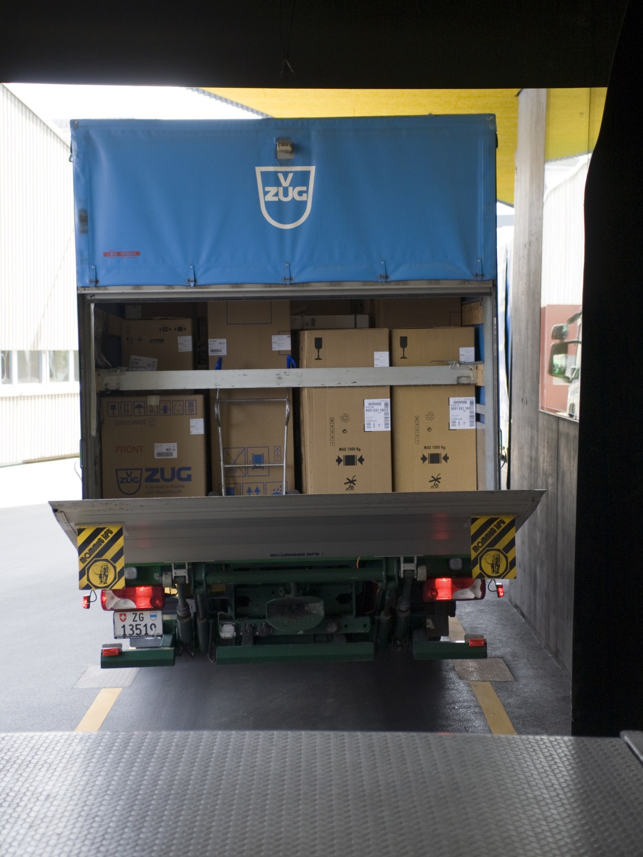 A V-Zug delivery truck loaded with cardboard boxes of white goods appliances.