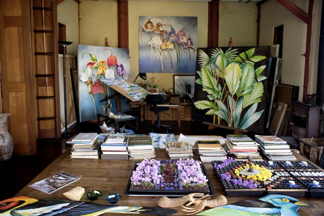 Artist Jenaro Mejia's studio with paintings, botanical artworks, and flower arrangements on display.